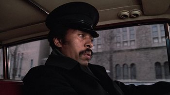 Movie still from “Trading Places” (1983), directed by John Landis – A man wearing a black hat and a black coat; Close Up shot, Low angle