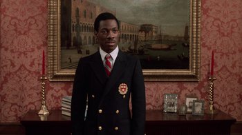 Movie still from “Trading Places” (1983), directed by John Landis – A man in a suit and tie standing in front of a painting; Medium shot, Low angle