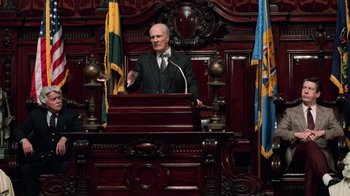Movie still from “Trading Places” (1983), directed by John Landis – A man in a suit and tie speaking at a podium; Medium shot, Low angle