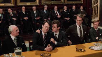 Movie still from “Trading Places” (1983), directed by John Landis – A group of men sitting at a long table; Medium shot, High angle