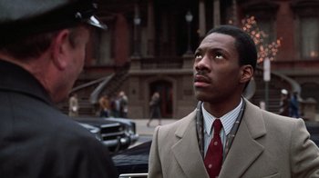 Movie still from “Trading Places” (1983), directed by John Landis – A man wearing a suit and tie standing next to another man in a suit; Close Up shot, Over the shoulder angle