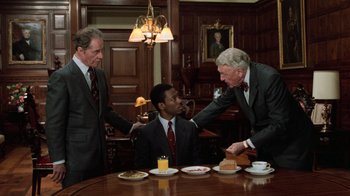 Movie still from “Trading Places” (1983), directed by John Landis – Three men in suits and ties at a dinner table; Medium shot, High angle