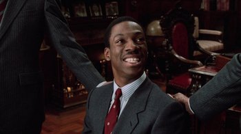 Movie still from “Trading Places” (1983), directed by John Landis – A man in a gray suit and a red tie; Close Up shot, Over the shoulder angle
