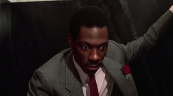Movie still from “Trading Places” (1983), directed by John Landis – A man wearing a suit and tie with a rose in his lapel; Close Up shot, High angle