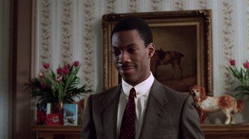 Movie still from “Trading Places” (1983), directed by John Landis – A man wearing a suit and tie in a room; Close Up shot, Over the shoulder angle