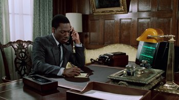 Movie still from “Trading Places” (1983), directed by John Landis – A man sitting at a desk talking on the phone; Medium shot, High angle