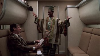 Movie still from “Trading Places” (1983), directed by John Landis – A man in a colorful outfit is standing in front of another man in a suit; Medium shot, High angle