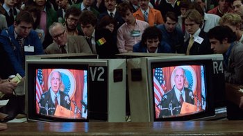 Movie still from “Trading Places” (1983), directed by John Landis – A crowd of people sitting in front of two televisons; Extreme Close Up shot, Over the shoulder angle