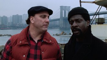 Movie still from “Trading Places” (1983), directed by John Landis – A couple of men standing next to each other near a body of water; Close Up shot, Over the shoulder angle