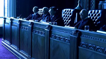 Movie still from “Traffic” (2000), directed by Steven Soderbergh – A group of judges sitting in a court room at night; Wide shot, Overhead angle