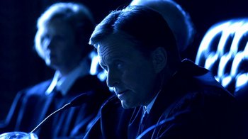 Movie still from “Traffic” (2000), directed by Steven Soderbergh – A man sitting in front of a microphone in a dark room; Close Up shot, High angle