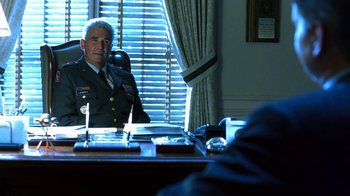 Movie still from “Traffic” (2000), directed by Steven Soderbergh – A man sitting at a desk in front of a window; Medium shot, Over the shoulder angle
