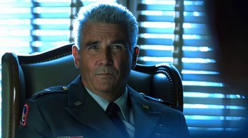 Movie still from “Traffic” (2000), directed by Steven Soderbergh – An older man in a uniform sitting in an office chair; Close Up shot, Low angle