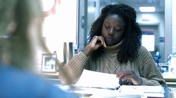 Movie still from “Traffic” (2000), directed by Steven Soderbergh – A woman sitting at a table looking at a piece of paper; Close Up shot, Over the shoulder angle
