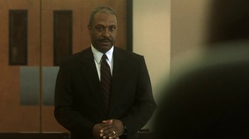 Movie still from “Traffic” (2000), directed by Steven Soderbergh – A man wearing a suit and tie standing in front of a mirror; Medium shot, Low angle