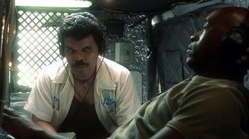 Movie still from “Traffic” (2000), directed by Steven Soderbergh – A man sitting next to another man in a vehicle; Medium shot, Over the shoulder angle