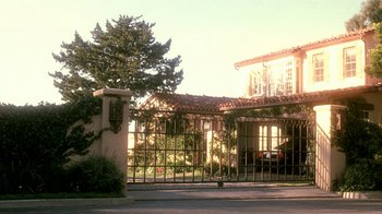 Movie still from “Traffic” (2000), directed by Steven Soderbergh – A gated driveway leading to a house with a tree in front of it; Extreme Wide shot, Low angle