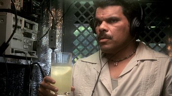 Movie still from “Traffic” (2000), directed by Steven Soderbergh – A man wearing headphones holding a glass of juice; Close Up shot, Over the shoulder angle