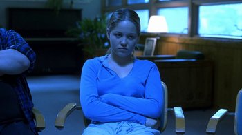Movie still from “Traffic” (2000), directed by Steven Soderbergh – A woman sitting in a chair with her arms crossed; Medium shot, Low angle