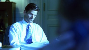 Movie still from “Traffic” (2000), directed by Steven Soderbergh – A man sitting at a table in front of a laptop computer; Medium shot, Over the shoulder angle