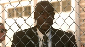 Movie still from “Traffic” (2000), directed by Steven Soderbergh – A man in a suit and tie behind a chain link fence; Close Up shot, Low angle