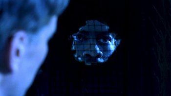 Movie still from “Traffic” (2000), directed by Steven Soderbergh – A man is reflected in the mirror of a person's face; Extreme Close Up shot, Over the shoulder angle