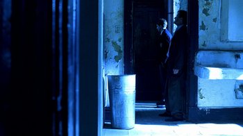 Movie still from “Traffic” (2000), directed by Steven Soderbergh – Two men standing in front of an open door of a building; Wide shot, Low angle