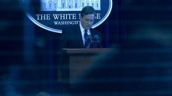 Movie still from “Traffic” (2000), directed by Steven Soderbergh – A man standing at a podium in front of a microphone; Medium shot, Over the shoulder angle