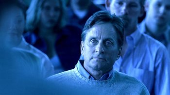 Movie still from “Traffic” (2000), directed by Steven Soderbergh – A person wearing a sweater with people in the background; Close Up shot, Over the shoulder angle