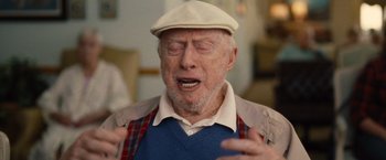 Movie still from “Trainwreck” (2015), directed by Judd Apatow – An older man with a white hat is singing; Close Up shot, Over the shoulder angle