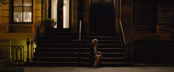 Movie still from “Trainwreck” (2015), directed by Judd Apatow – A woman sitting on the steps of a building; Wide shot, Over the shoulder angle