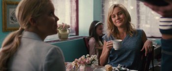 Movie still from “Trainwreck” (2015), directed by Judd Apatow – A woman sitting at a table holding a cup of coffee; Medium shot, Over the shoulder angle