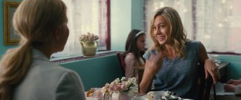 Movie still from “Trainwreck” (2015), directed by Judd Apatow – A woman sitting at a table with a bouquet of flowers in front of her; Medium shot, Over the shoulder angle
