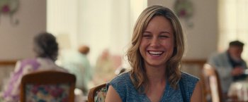 Movie still from “Trainwreck” (2015), directed by Judd Apatow – A woman smiles brightly while sitting at a table; Close Up shot, Over the shoulder angle