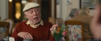 Movie still from “Trainwreck” (2015), directed by Judd Apatow – An older man is sitting at a table talking; Close Up shot, Over the shoulder angle