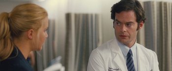 Movie still from “Trainwreck” (2015), directed by Judd Apatow – A man wearing a lab coat looks at the camera; Close Up shot, Over the shoulder angle