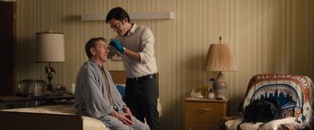 Movie still from “Trainwreck” (2015), directed by Judd Apatow – A man in a room with a man sitting on a bed; Medium shot, Over the shoulder angle