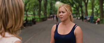 Movie still from “Trainwreck” (2015), directed by Judd Apatow – A woman in a blue shirt is walking down the street; Medium shot, Over the shoulder angle