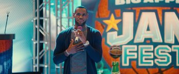 Movie still from “Trainwreck” (2015), directed by Judd Apatow – A man is holding a microphone while standing in front of an audience; Medium shot, Over the shoulder angle