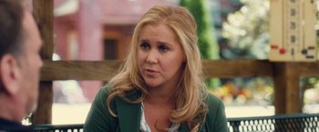 Movie still from “Trainwreck” (2015), directed by Judd Apatow – A woman with long blonde hair wearing a green jacket; Close Up shot, Over the shoulder angle