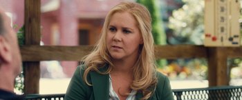 Movie still from “Trainwreck” (2015), directed by Judd Apatow – A woman with long blonde hair wearing a green jacket; Close Up shot, Over the shoulder angle