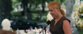 Movie still from “Trainwreck” (2015), directed by Judd Apatow – A woman is speaking into a microphone outside; Medium shot, Over the shoulder angle