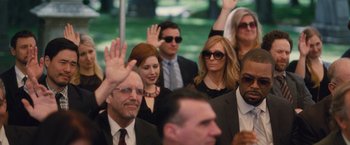 Movie still from “Trainwreck” (2015), directed by Judd Apatow – A group of people sitting in a room waving at something; Medium shot, Over the shoulder angle