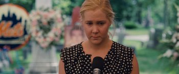 Movie still from “Trainwreck” (2015), directed by Judd Apatow – A woman is holding a microphone in her hand; Close Up shot, Over the shoulder angle