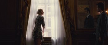 Movie still from “Trainwreck” (2015), directed by Judd Apatow – A woman standing in front of a window looking outside; Wide shot, Over the shoulder angle