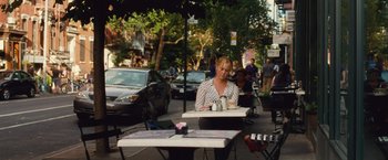 Movie still from “Trainwreck” (2015), directed by Judd Apatow – A woman sitting at an outdoor table on the sidewalk; Wide shot, Over the shoulder angle