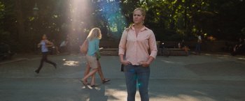 Movie still from “Trainwreck” (2015), directed by Judd Apatow – A woman standing on the side of the road with her hands in her pockets; Wide shot, Over the shoulder angle