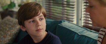 Movie still from “Trainwreck” (2015), directed by Judd Apatow – A boy sitting on a couch looking at the camera; Close Up shot, Over the shoulder angle
