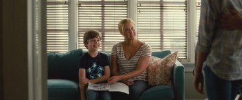 Movie still from “Trainwreck” (2015), directed by Judd Apatow – A woman sitting next to a young boy on a couch; Medium shot, Over the shoulder angle