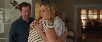 Movie still from “Trainwreck” (2015), directed by Judd Apatow – Two women hugging each other in a living room; Medium shot, Over the shoulder angle